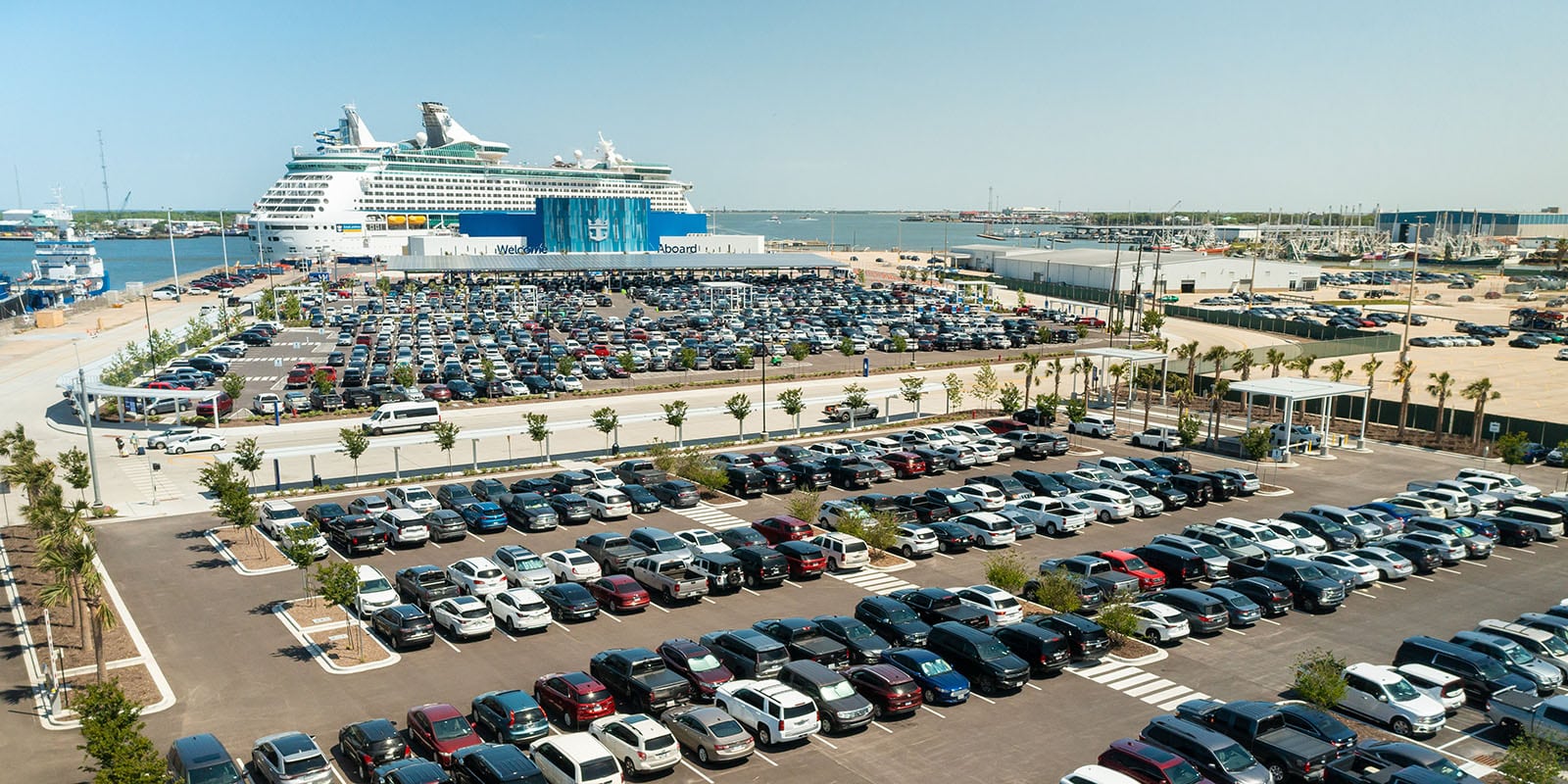 Aerial view of a parking lot with a cruise ship in the background.